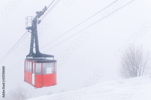 Red Ski lift in the background of the winter mountains. The red trailer of the old cable car moves to the mountain top of the ski resort. Retro gondola. © Т Т