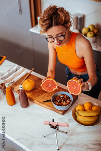 Joyful positive woman showing two grapefruit halves