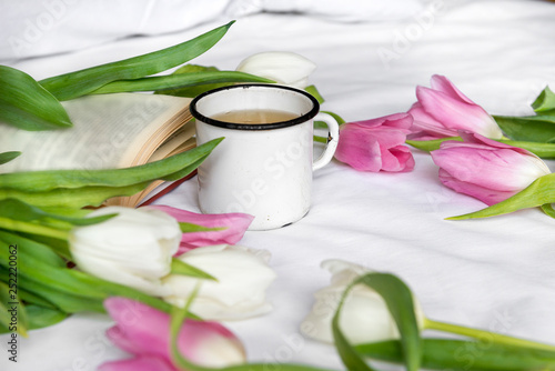 mug, tea, white and pink tulips, a book on a white sheet