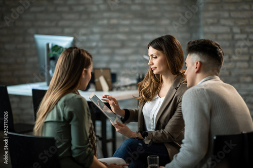 Financial advisor and young couple using touchpad while having a meeting in the office.