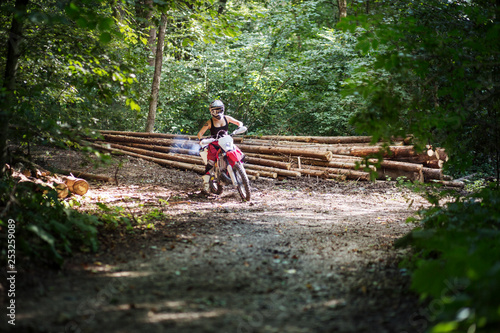 Female motocross rider accelerating into a corner in the woods