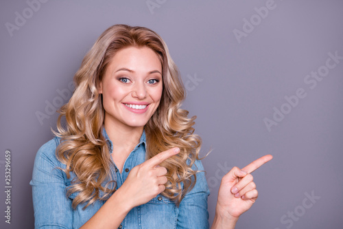 Close up photo glad amazing beautiful she her lady hold arms hands point empty space propose offer buy buyer new product wearing casual jeans denim shirt clothes outfit isolated grey background