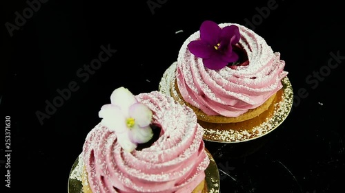 smooth panorama down on two pink zephyr cookies decorated with violet and white flowers served on black © alkiona_25