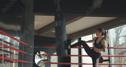 Kickboxing woman training punching bag in fitness studio fierce strength fit body