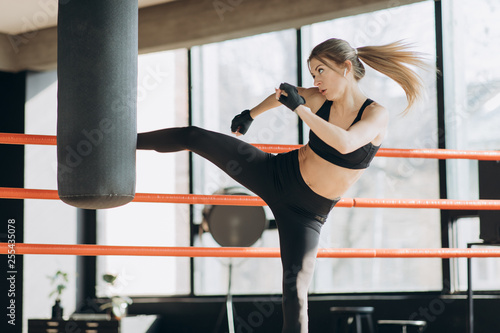 Kickboxing woman training punching bag in fitness studio fierce strength fit body