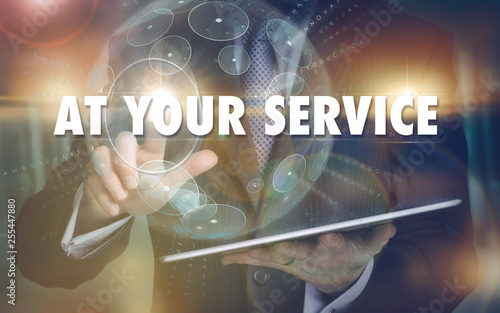 A hand selecting a At Your Service business concept on a futuristic computer display.