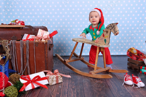 A small boy dressed up as an elf stands in Christmas decorations. © fotodrobik