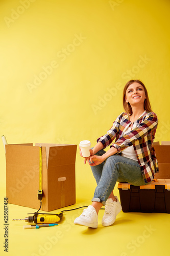 Move. Woman drinking coffee sitting on a tool box. Studio © oleg_chumakov