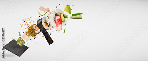 Pieces of delicious japanese sushi frozen in the air. Isolated on light grey background © Lukas Gojda