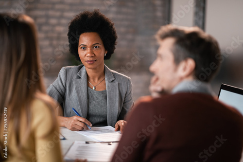 African American financial consultant listening to her clients during a meeting.