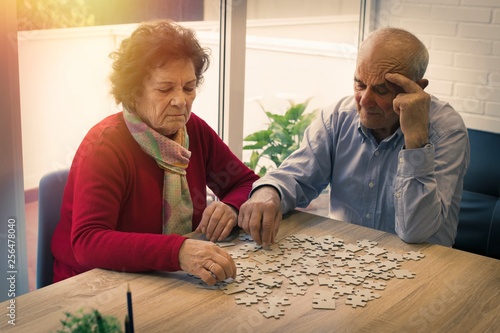 older couple making puzzle on the table © carballo