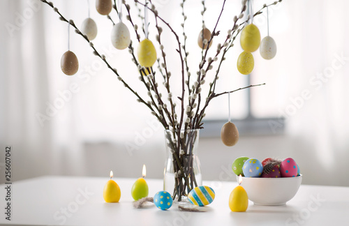 holidays and object concept - pussy willow branches decorated by easter eggs in vase and candles on table © Syda Productions