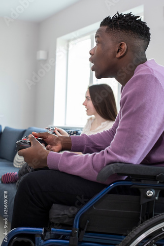 Teenage Boy In Wheelchair Playing Computer Video Game With Freind At Home © Daisy Daisy