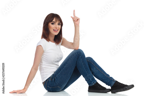 Young Woman Is Sitting On Floor, Pointing Up And Talking © studioloco