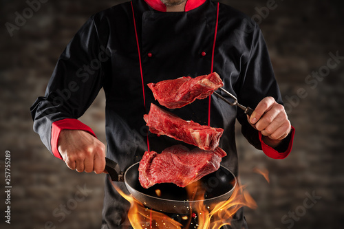 Closeup of chef throwing raw beef steaks © Jag_cz
