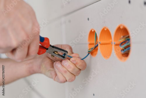 Handyman stripping an electric wire © contrastwerkstatt