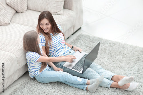 mother and daughter sitting on the floor in a cozy living room © ASDF