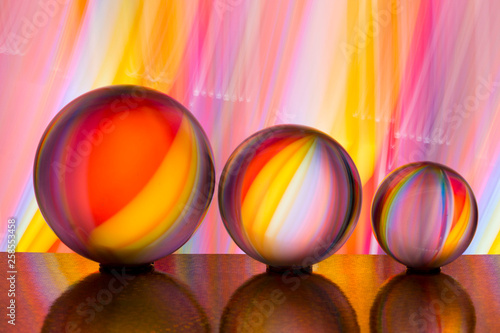 A row of three crystal balls with multicolored light painting behind them © Helen Davies