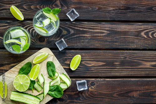 cold water with ice, cucumber and lime juice for summer healthy drink on wooden background top view mock up © 9dreamstudio