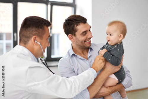 medicine, healthcare, pediatry and people concept - father with baby and doctor with stethoscope at medical office in hospital © Syda Productions