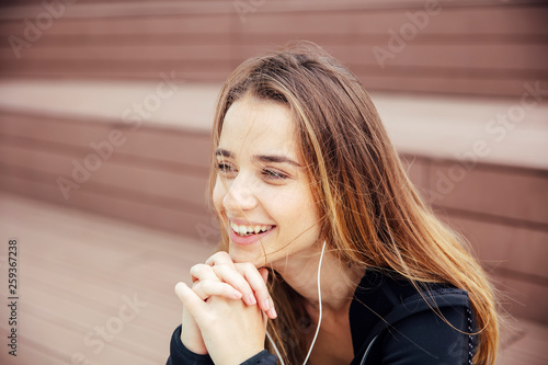 Smiling young woman with smartphone and headphones listening to music © Boggy