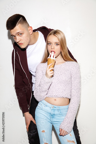 We are friends. Close up fashion portrait of two young cool hipster girl and boy wearing jeans wear. Studio shot of two models having fun and making funny faces. © master1305