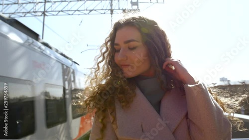 Young curly girl extraordinary dreamer waiting for a train at the railway station in Sunny day time city concept © Iaroslav