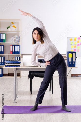 Young female employee doing exercises at workplace  © Elnur