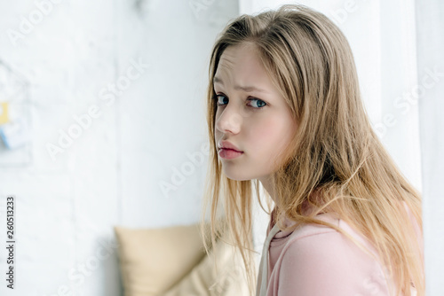 Sad teenage kid in pink hoodie looking at camera © LIGHTFIELD STUDIOS