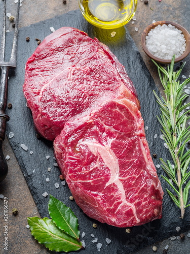 Raw Rib eye steak or beef steak on the graphite board with herbs and spices. © volff