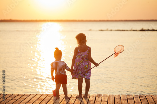 Happy sisters kids playing on beach at the sunrise time with fishing net. Family and friendships concept. Summer time © shcherban