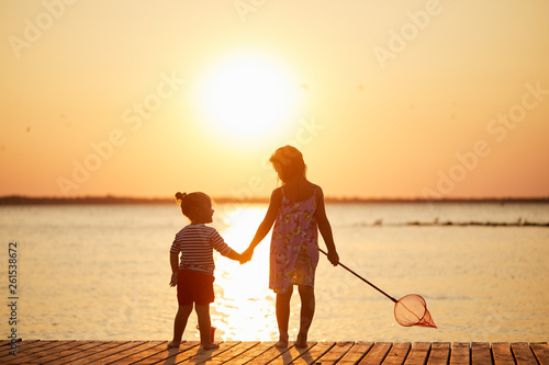 Happy sisters kids playing on beach at the sunrise time with fishing net. Family and friendships concept. Summer time © shcherban