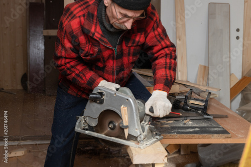Senior man works as a carpenter with circular saw in his workshop. Active old age © sonate