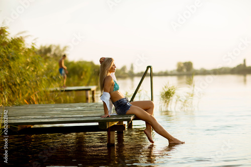 Young woman sitting on the pier on the lake © Boggy