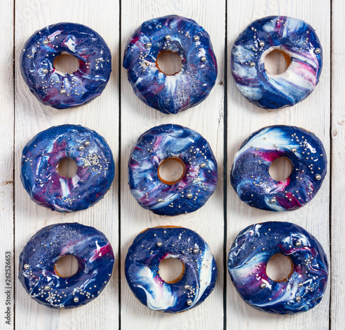 Set of donuts with cosmic icing and silver sprinkles on wooden background. © Nataliia Pyzhova