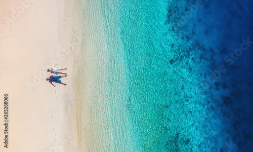 Aerial view of a people couple on the beach on Bali, Indonesia. Vacation and adventure. Beach and turquoise water. Top view from drone at beach, azure sea and relax couple. Travel and relax - image © Biletskiy Evgeniy