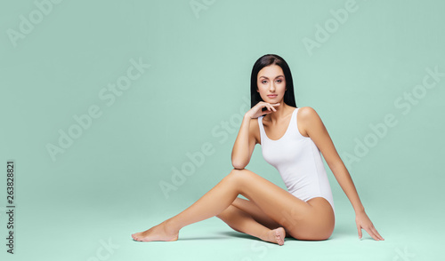 Athletic and healthy girl posing in white bodysuit. Fit and sexy woman in underwear swimsuit. Slim shape, nutrition, sport, fitness and diet concept. © Maksim Šmeljov