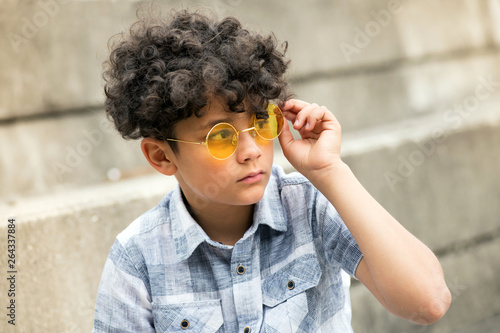 Young curly headed boy with trendy yellow shades © photology1971