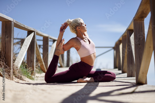 Caucasian blonde woman practicing yoga in the beach © javiindy
