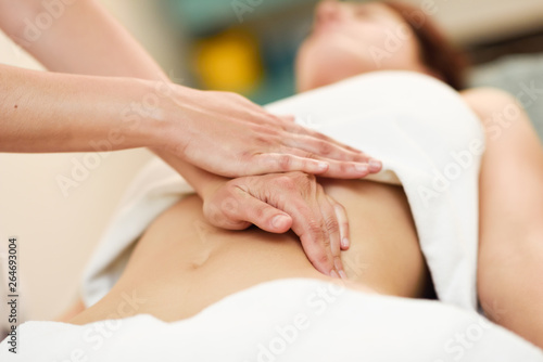 Therapist applying pressure on belly. Hands massaging woman abdomen. © javiindy