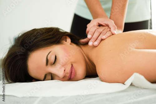 Young woman receiving a back massage in a spa center. © javiindy